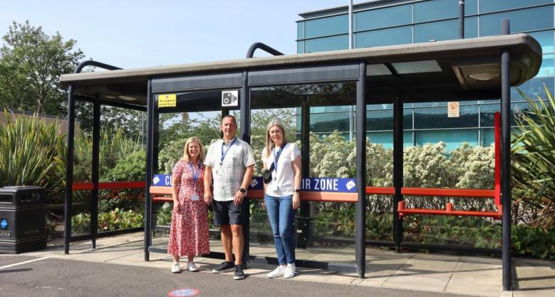 Three people standing in front of a bus stop