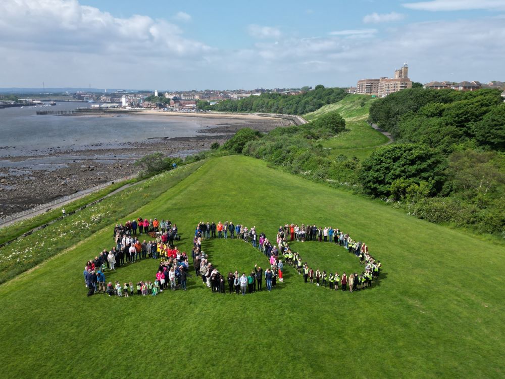 People from North Shields standing in the shape of a number 800 with the Fish Quay behind 