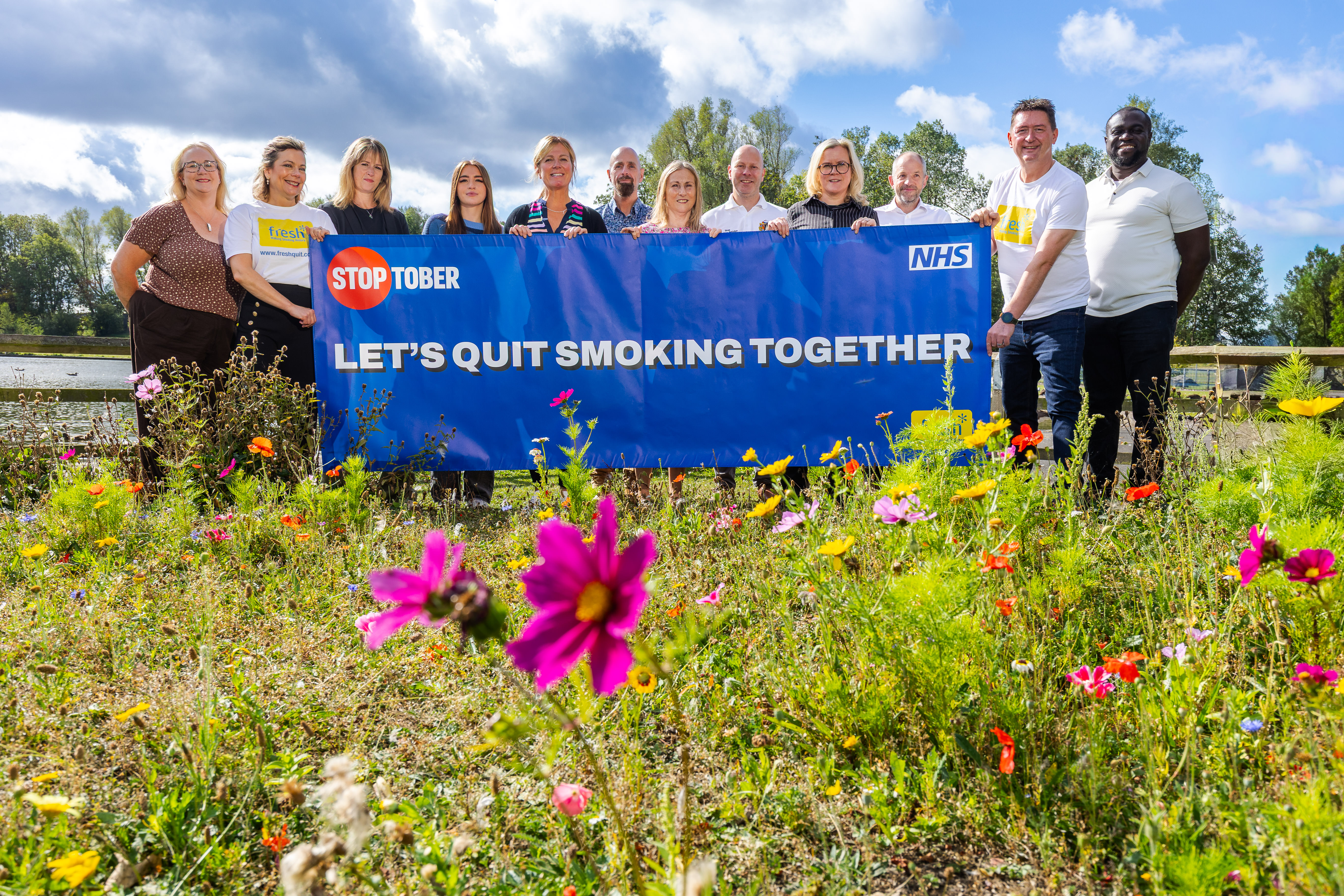 Group of people holding sign saying 'let's quit smoking together'
