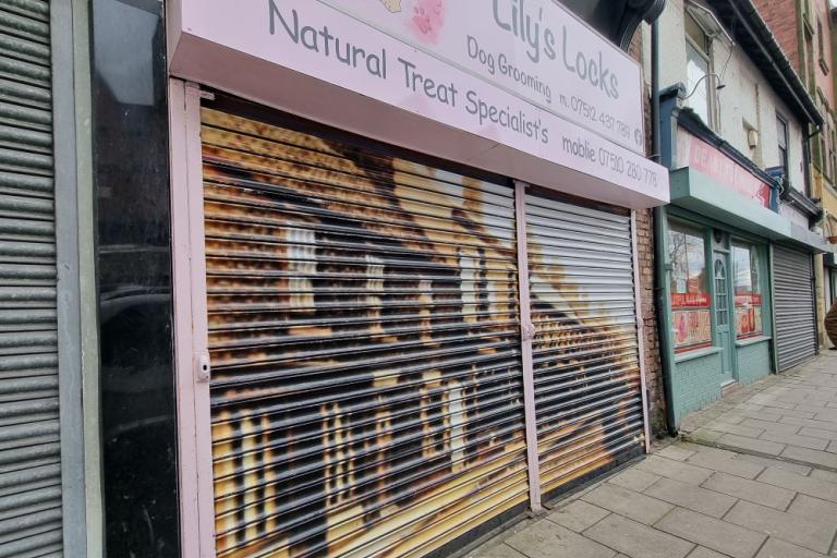 A colour photo of a pet grooming shop with a vinyl of a black and white photo covering its shutters