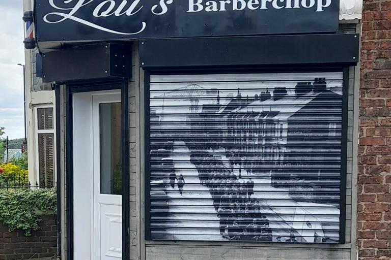 A colour photo of a barber shop with a vinyl of a black and white photo covering its shutters