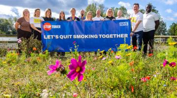 Group of people holding sign saying 'let's quit smoking together'