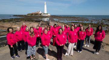 Adopt North East colleagues in pink Adopt NE jumpers in front of St Mary's Lighthouse